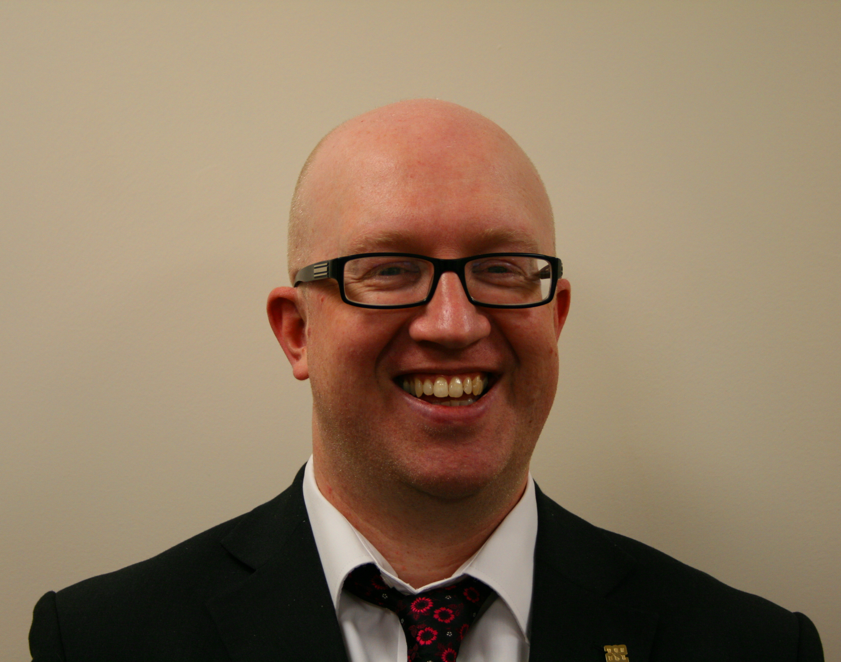 Smiling male bald teacher with glasses against white background