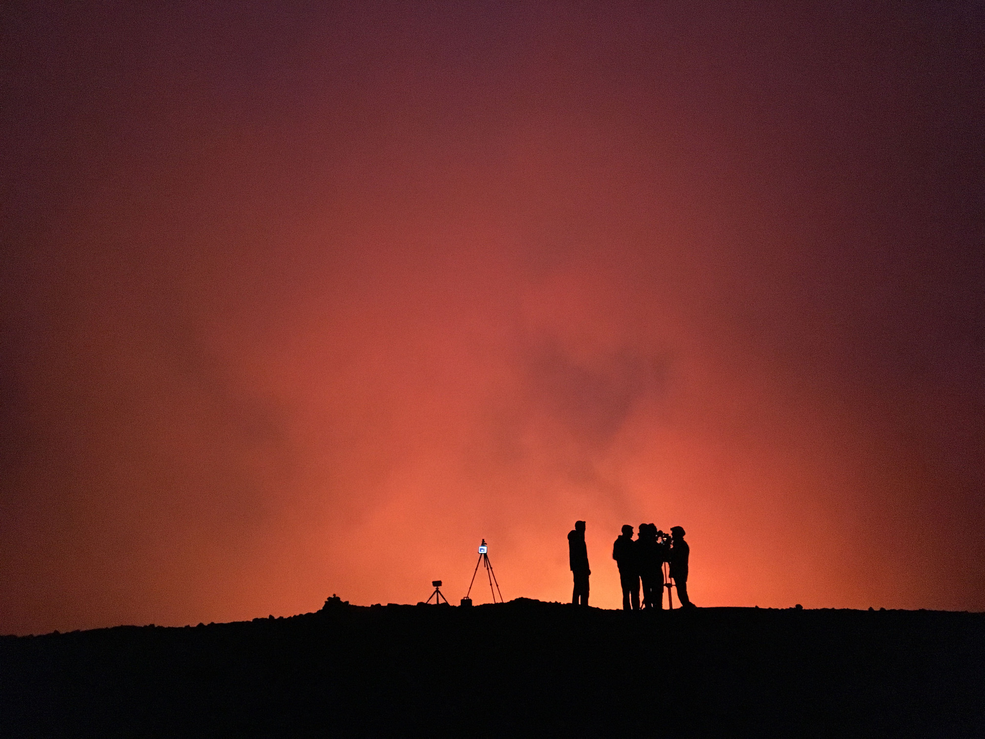 Camera men and equipment silhouetted against a red sky