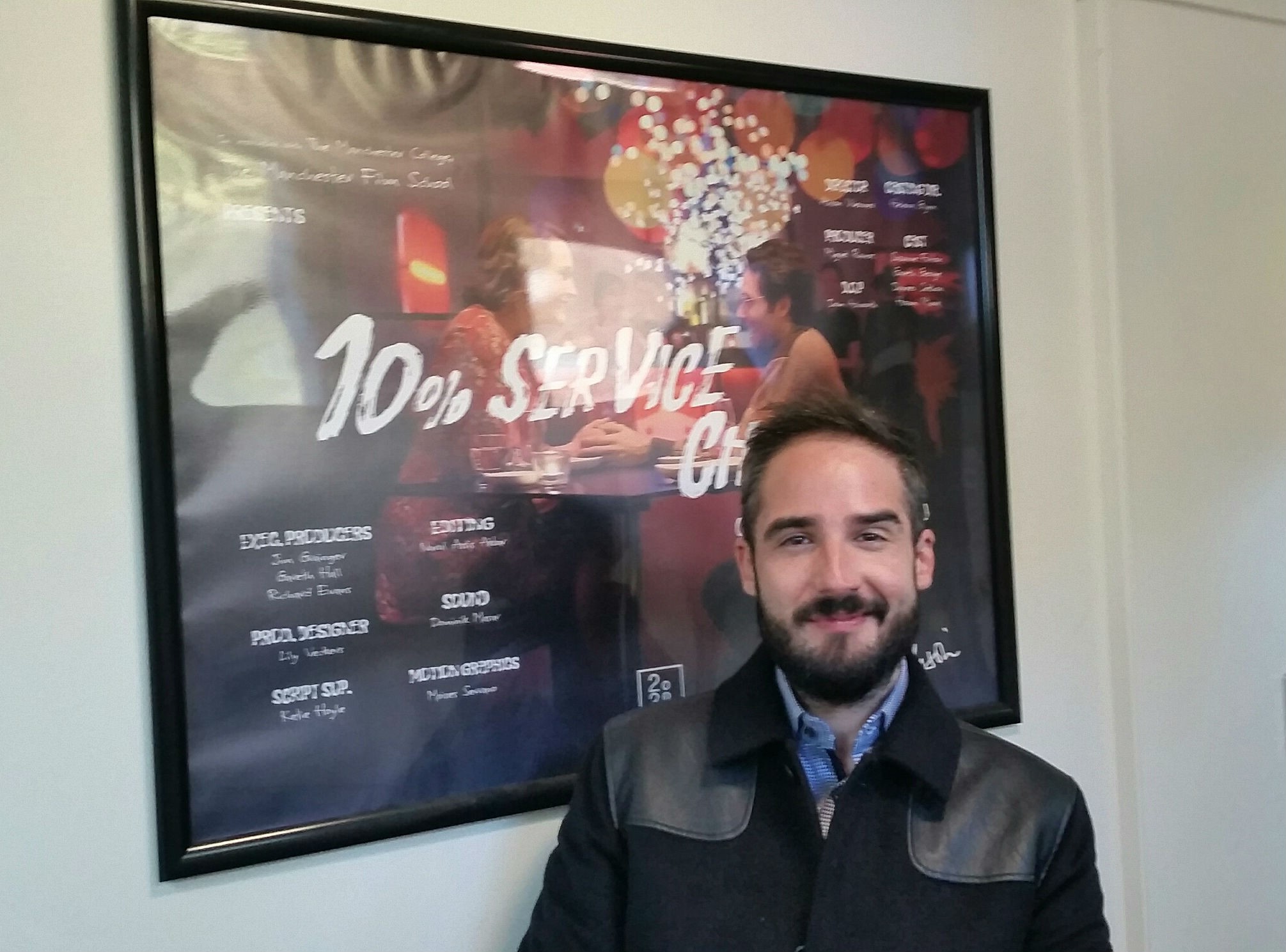 Man smiles infront of movie poster