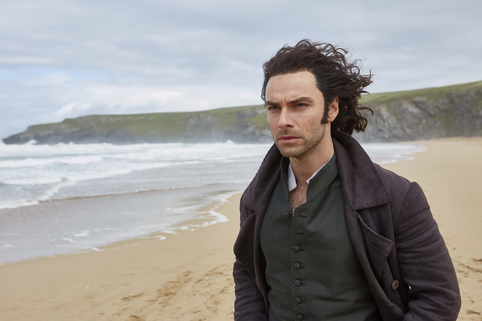 The actor Aidan Turner, playing Poldark on a windswept beach